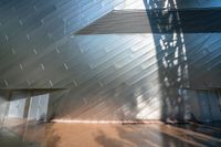 an abstract structure that is cladding in silver and brown tones with sunlight coming through