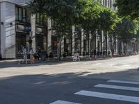 a traffic sign on an empty city street during the day, as people wait at the crossing