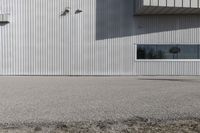 the building is covered in white corrugated panels and a red fire hydrant sitting outside