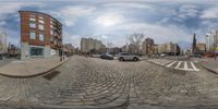 this is a fish eye lens showing cars and a building in the city center with some buildings