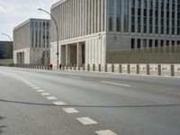 an empty street next to large buildings with windows and pillars on each side of them