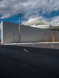 a white wall, which is in front of two palm trees, in the middle of the street