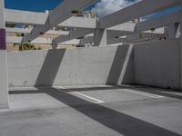 an empty parking lot has some sun casting onto the wall and windows above it with no shadows