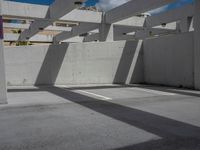 an empty parking lot has some sun casting onto the wall and windows above it with no shadows