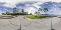 a 360 - ray view of a park with benches, grass and a large building near water