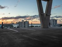 an empty parking lot with tall buildings in the background at sunset, surrounded by a boardwalk