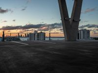 an empty parking lot with tall buildings in the background at sunset, surrounded by a boardwalk