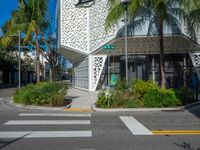 palm trees and flowers near a white building with a sign on it that reads green