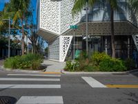 palm trees and flowers near a white building with a sign on it that reads green