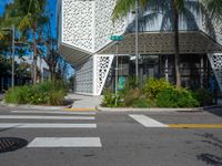 palm trees and flowers near a white building with a sign on it that reads green