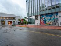 street intersection with painted mural in back ground and yellow cautions to left of corner