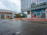 street intersection with painted mural in back ground and yellow cautions to left of corner