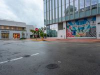 street intersection with painted mural in back ground and yellow cautions to left of corner