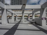 a photo of a parking lot with a sky scraper behind the area and street sign