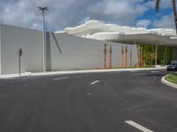 this is the empty parking lot of a large white building near a palm tree lined street