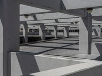 a parking garage with multiple long columns and overhead lamps and light poles, looking into an aisle that has been built from concrete and cement