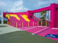 a tennis court with stairs, parking space and a pink structure in the middle of it