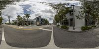 this 360 - camera photo shows a street with buildings and plants on each side of it