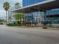 a stop sign in front of an office building with palm trees on the side of the road