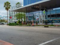 a stop sign in front of an office building with palm trees on the side of the road