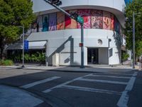a crosswalk in front of an art gallery with a mural on the side of the building