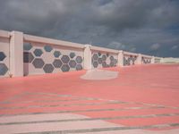 the red paved parking lot is lined with hexagons and white concrete walls