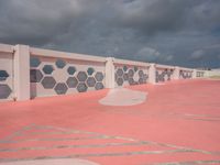 the red paved parking lot is lined with hexagons and white concrete walls