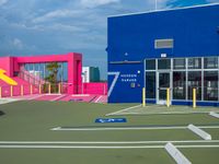 the parking lot is empty in front of the building, and painted blue and pink
