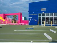 the parking lot is empty in front of the building, and painted blue and pink