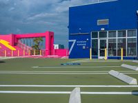 the parking lot is empty in front of the building, and painted blue and pink