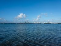 a blue body of water with a bunch of boats floating on it, and clouds in the background