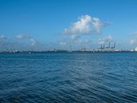 a blue body of water with a bunch of boats floating on it, and clouds in the background