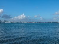 a blue body of water with a bunch of boats floating on it, and clouds in the background