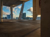 a empty parking lot next to an open sidewalk with buildings in the distance at sunset