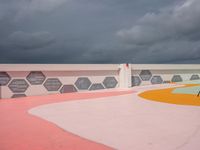 an outside basketball court with a cloudy sky over it and lots of different colored floors