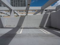 an empty parking garage with three white lines on the ground in front of a sky and city view