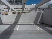 an empty parking garage with three white lines on the ground in front of a sky and city view