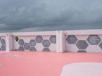 a long white building with pink and black tiles along the walls of the building are hexagons