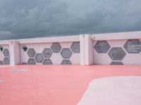 a long white building with pink and black tiles along the walls of the building are hexagons