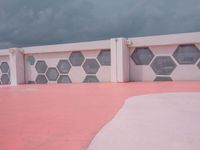 a long white building with pink and black tiles along the walls of the building are hexagons