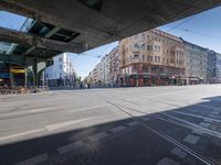 a street with two trains on it and a few people walking under an overpass