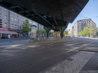 a street with two trains on it and a few people walking under an overpass