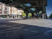 a street with two trains on it and a few people walking under an overpass