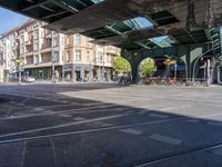 a street with two trains on it and a few people walking under an overpass