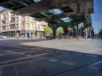 a street with two trains on it and a few people walking under an overpass