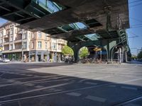 a street with two trains on it and a few people walking under an overpass