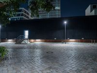 a brick paver and steps at night with light poles around it and some tall building