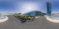 a panoramic picture shows the view from inside of an airport terminal with lots of windows, and grass and trees, and a sky