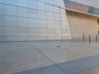 an empty building with an exterior that has glass and concrete architecture and a bench in front of the building