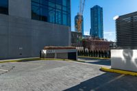 a parking lot next to tall buildings and a street corner under a bright blue sky